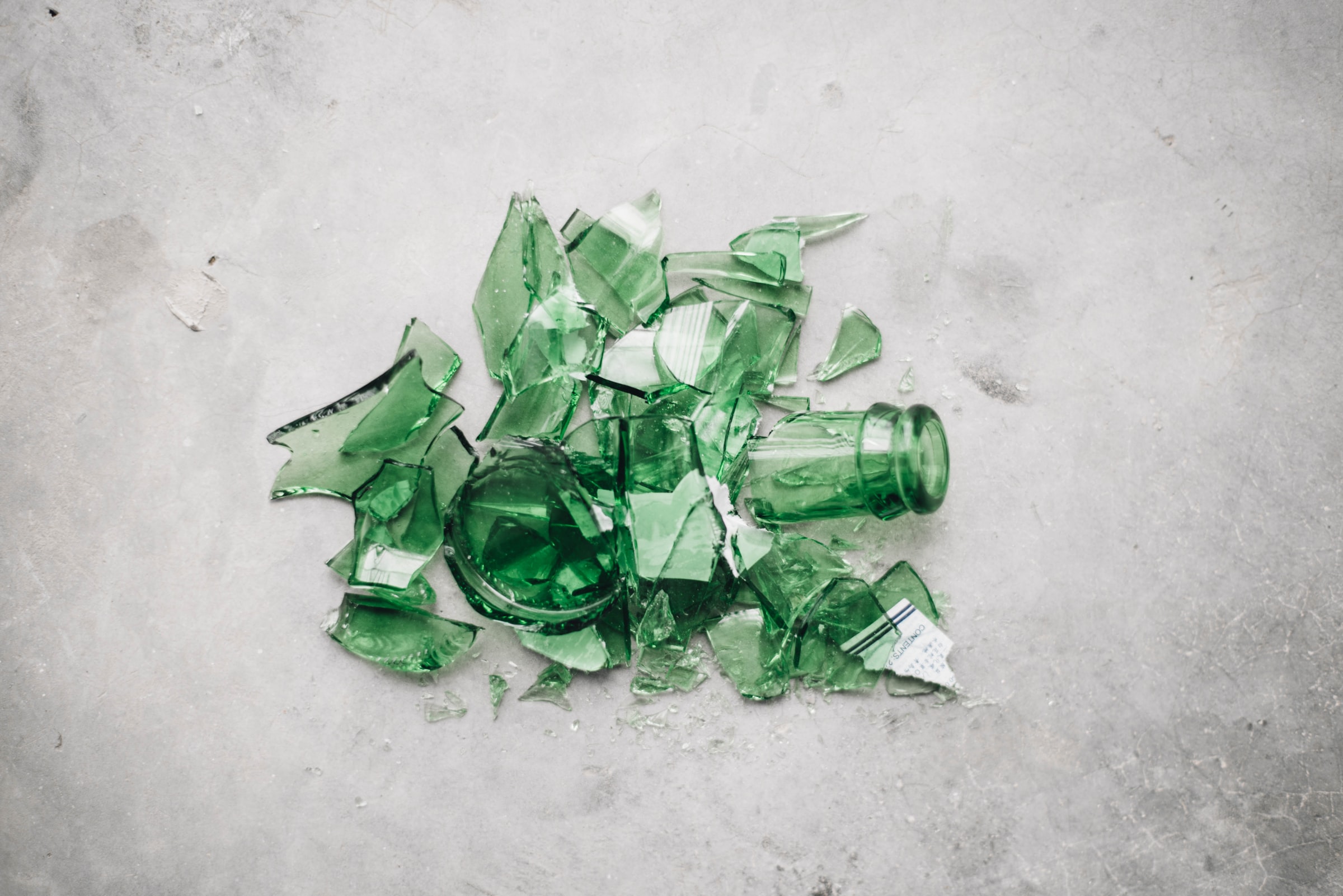 broken green glass bottle on the ground by CHUTTERSNAP on Unsplash