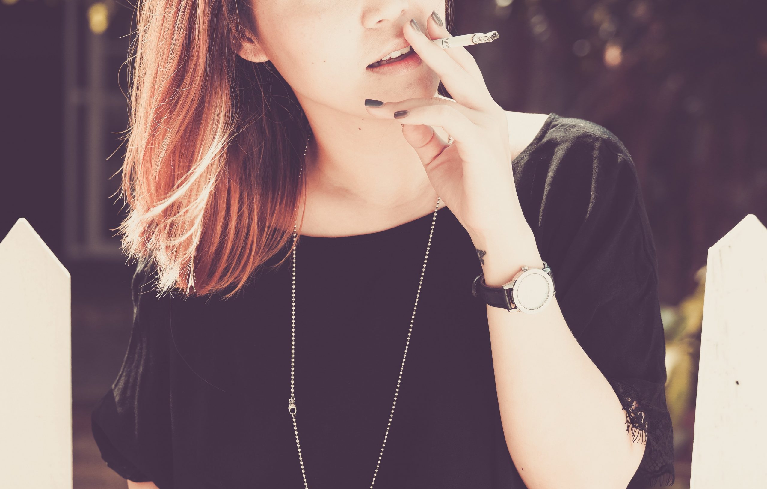 'Young woman smoking a cigarette outside' by Thong Vo on Unsplash